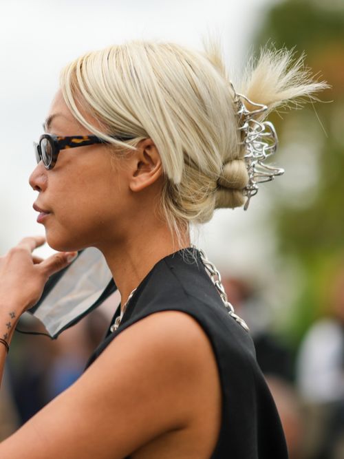 Vanessa Hong trägt eine schwarze Weste und Sonnenbrille mit einer Haarklammer-Frisur auf der Paris Fashion Week.