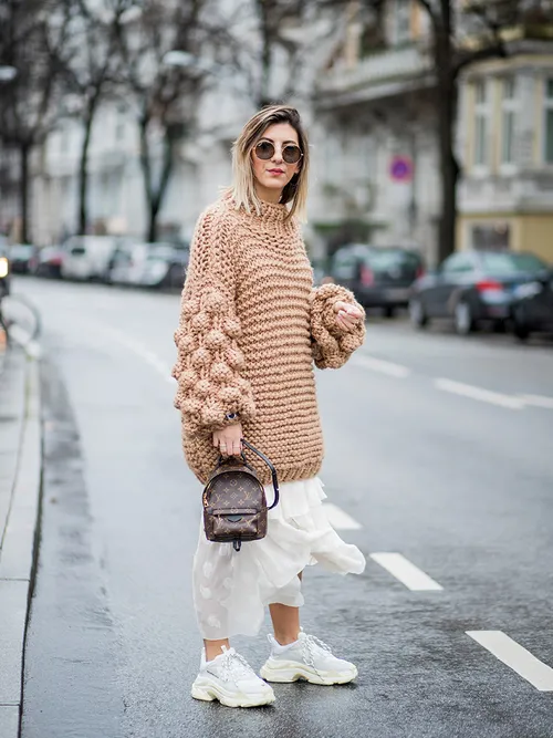 White Balenciaga sneakers worn with white skirt and beige sweater