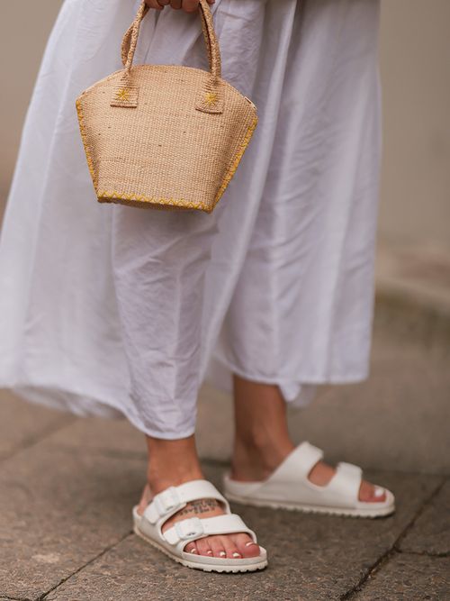 Close up von weißen Birkenstock Sandalen zu einem Rock.