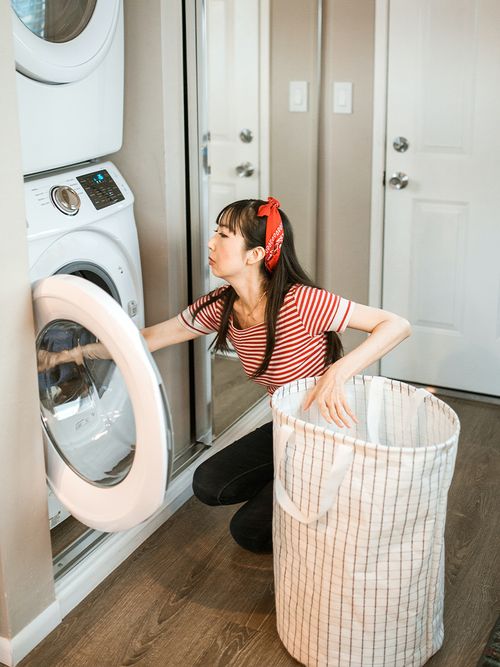 Frau mit rotem Top befüllt eine Waschmaschine.