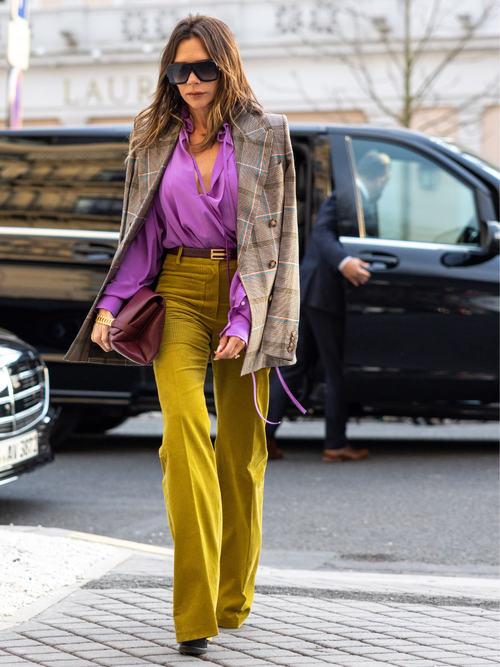 Victoria Beckham trägt Smart Casual auf der Paris Fashion Week. Eine rosa Bluse, ausgestellte High Rise Hose und einen Blazer über die Schultern