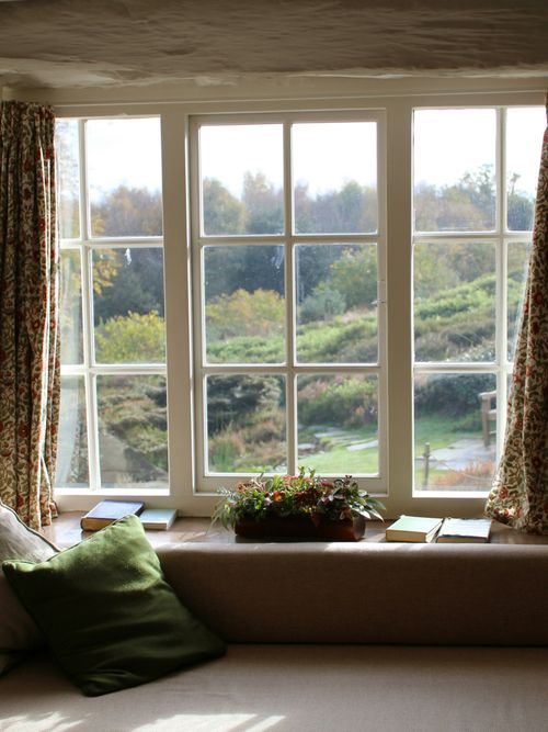 Interior-Foto von einem Fenster, das auf der Fensterbank eine Pflanze, Buch und Polster zeigt.