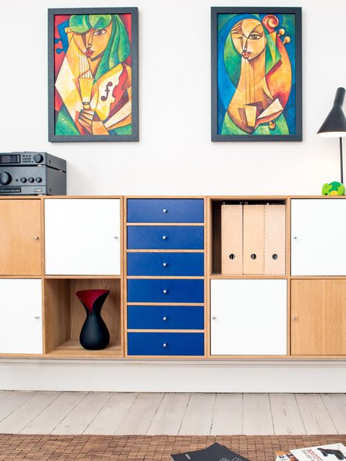 Eine Foto von einer bunten Kommode von Ikea mit Bildern und einem Teppich.