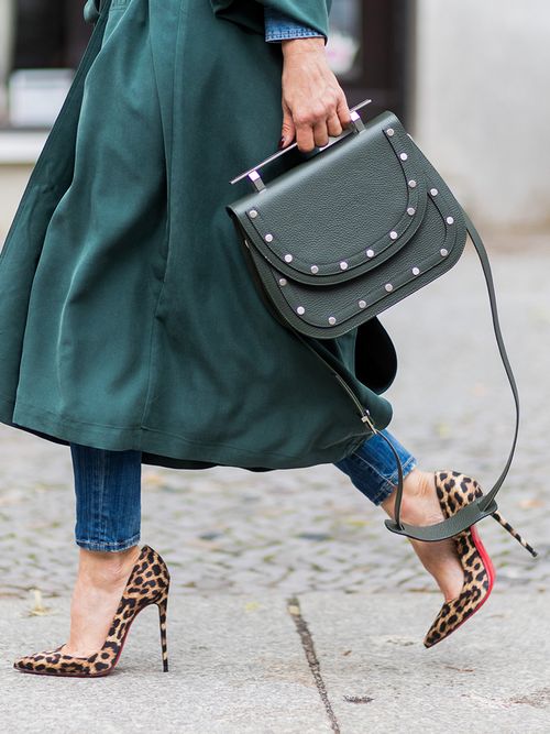 Close up von Leo-Pumps von Christian Louboutin zu einem flaschengrünen Mantel und Handtasche.