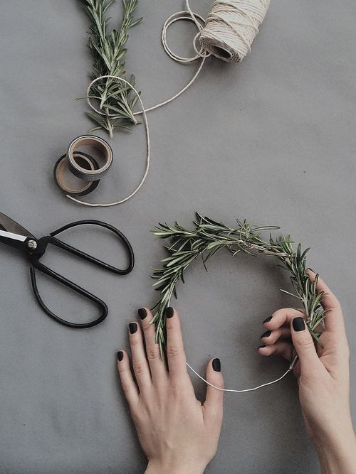 Zwei Hände, die auf einem grauen Untergrund einen Kranz binden.