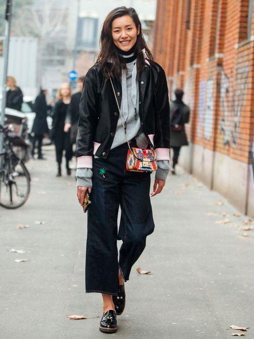 Model Liu Wen auf der Milan Fashion Week. Sie trägt eine schwarze Jacke, Hoodie und Jeans, dazu eine Furla Tasche.