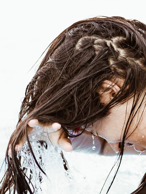 Frau mit nassen Haaren die sie kopfüber hält