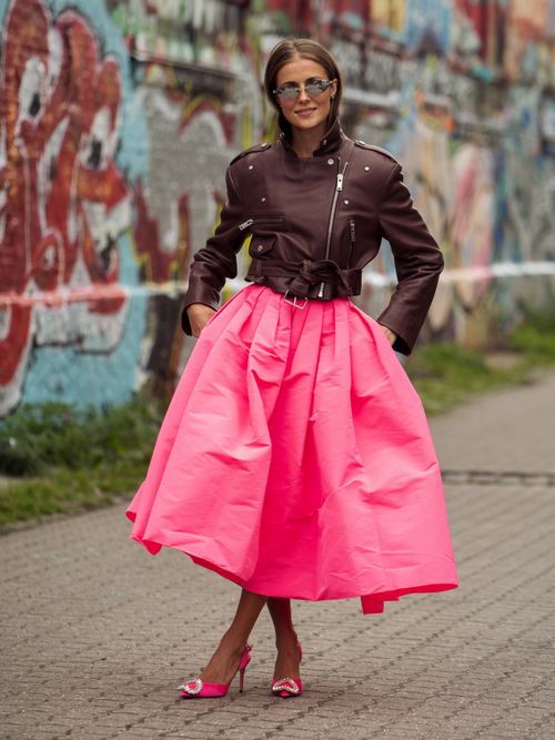 Nina Sandbech trägt eine kurze Lederjacke, einen pinken Tellerrock, Sonnenbrille und High Heels auf der Copenhagen Fashion Week.