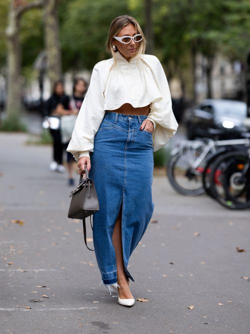 Street Style Look von der Paris Fashion Week, wo ein Gast eine Volantbluse mit Jeansrock trägt.