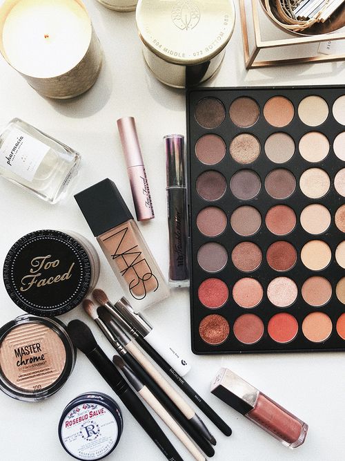 Eine Aufsicht auf einen weißen Tisch voller Beauty-Make-up Produkte.