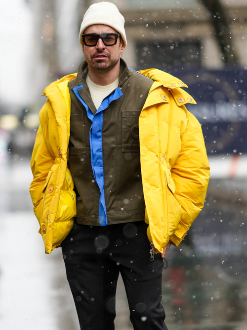 Influencer Alex Badia trägt eine gelbe Daunenjacke mit einem Hemd und Jeanshose in New York