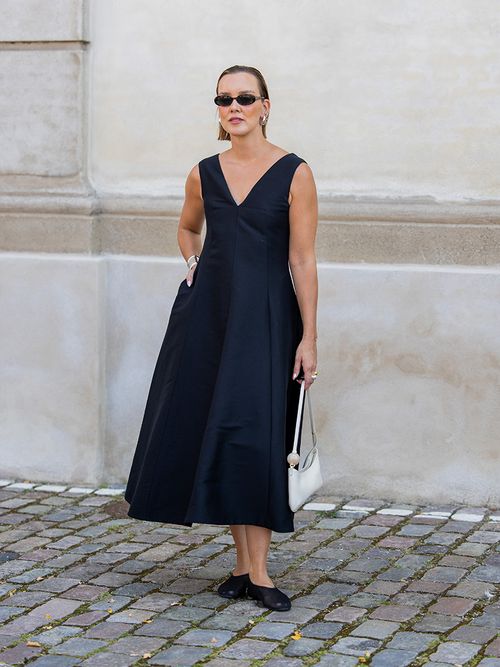 Tina Haase trägt ein dunkelblaues Kleid, schwarze Ballerina, eine silberfarbene Tasche und Sonnenbrillen auf der Copenhagen Fashion Week.