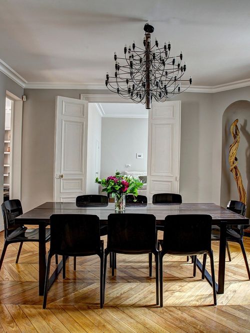 Herrschaftliches Esszimmer mit schwarzen Möbeln und grauer Wand.