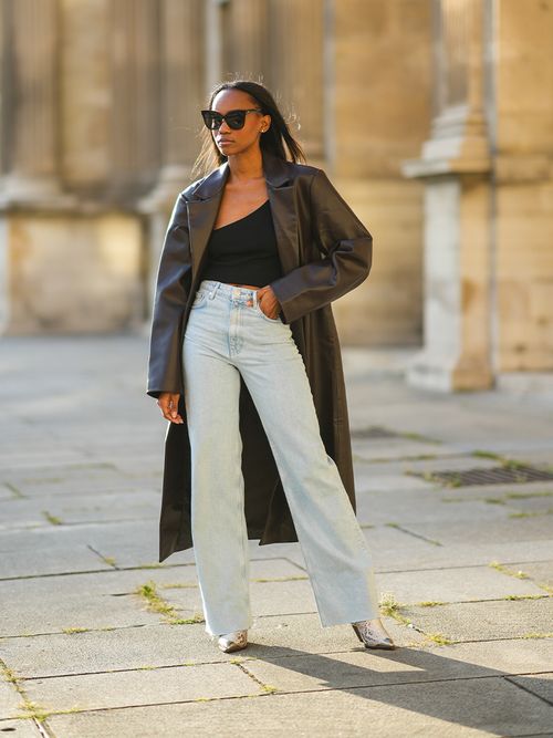Streetstyle mit einer ausgestellten Jeans einem cropped Top und einem Ledermantel.
