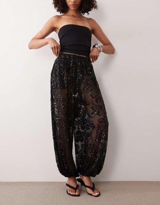 Tfnc pantaloni neri trasparenti con paillettes floreali, vita elasticizzata e gamba a palloncino-Nero