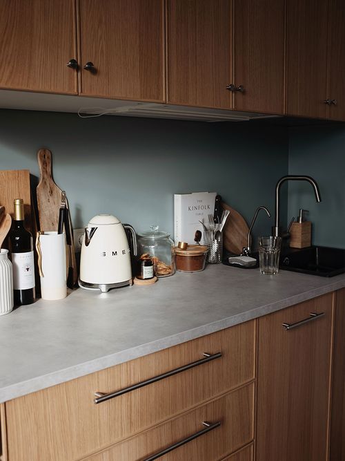 Küchenzeile in Eiche mit einer hellgrünen Rückwand und einem Smeg Wasserkocher.
