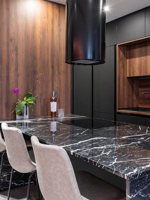 Küche aus Walnussholz und einer Kücheninsel aus schwarzem Marmor.