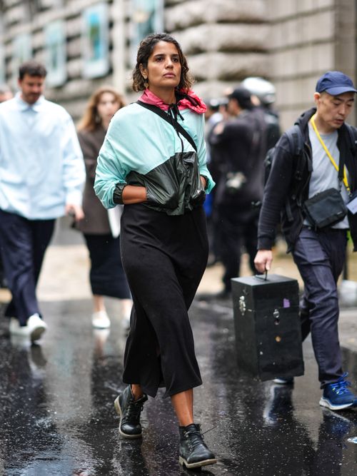 Street Style Look von der Paris Fashion Week, wo ein Gast eine Trainingsjacke, schwarzen Rock und Schnürboots trägt.