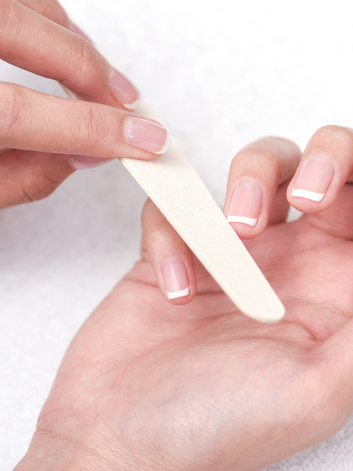 Close-up von einer Frauenhand die sich gerade die Nägel feilt