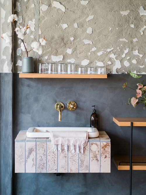 Waschbecken mit goldenen Amatruen und einem Holzregal.