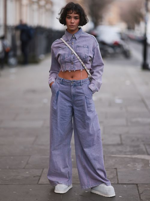 Edie Liberty Rose seen wearing a matching look with a cropped purple jeans blouse and a wide leg purple jeans with bright flat shoes before the Mark Fast show during London Fashion Week.