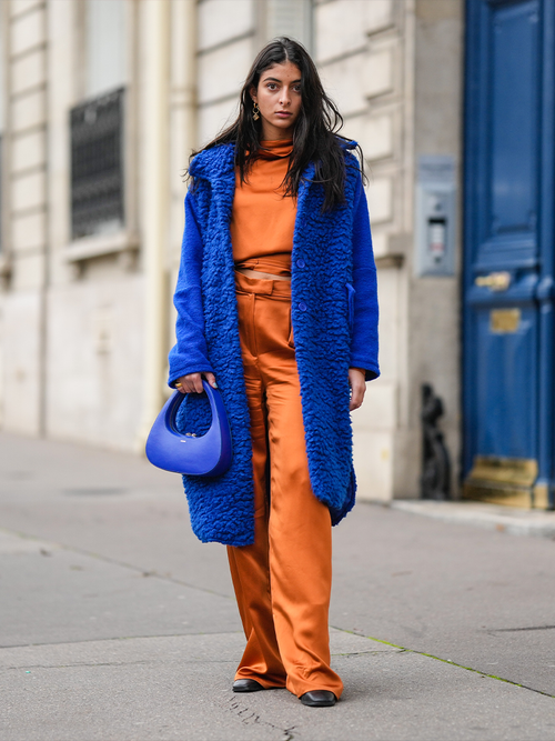 Streetstyle mit einer orangefarbeneh Hose und Oberteil zu einem blauen Teddymantel und einer kleinen Handtasche.
