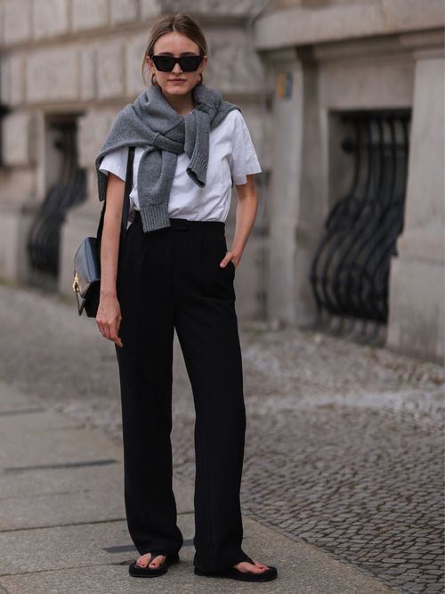 Sophie Pirrung trägt ein weißes T-Shirt mit einem Pullover um die Schultern, dazu eine schwarze Denim und Sonnenbrille in Berlin.