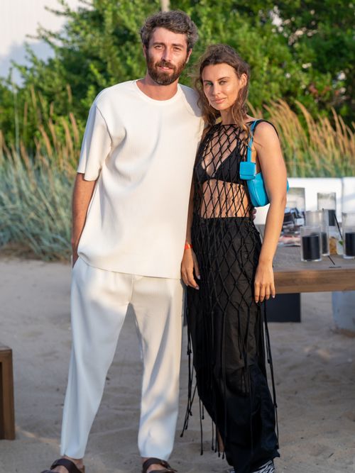 Maximilian Eicke trägt einen Monochrom-Look in Weiß und Irina Eicke ein schwarzes Häkel Kleid mit blauer Tasche auf einer Party in New York.