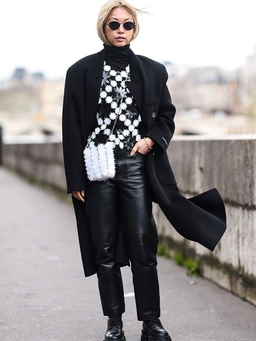 Streetstyle mit einer Lederhose, einem schwarz/weißen Pulli und einem schwarzen Wollmantel.