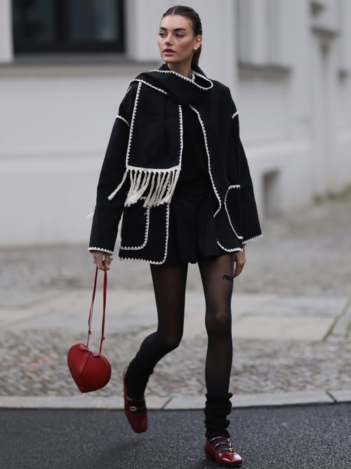 Celine Bethmann trägt eine Schal-Jacke aus Wolle mit Strickstulpen, Ballerinas und einer kleinen Tasche in Herzform in Berlin.