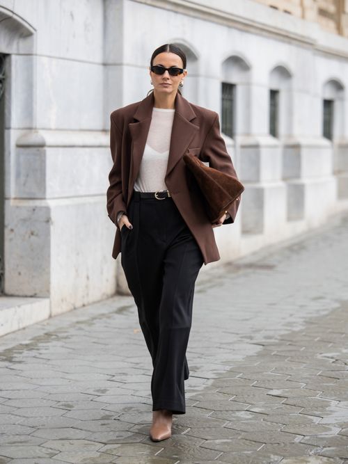 Zina Charkoplia trägt einen Business-Blazer in Braun mit schwarzer Hose und nudefarbenen Heels in Barcelona.
