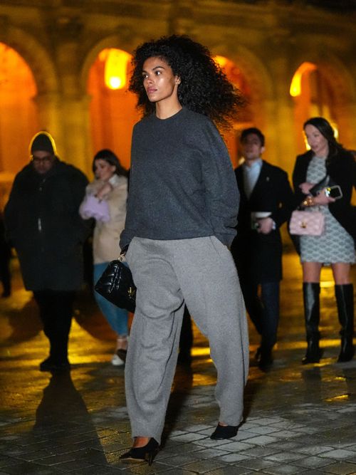 Tina Kunakey wears a gray oversized pullover , gray wide-leg pants, a leather bag, outside Louis Vuitton, during the Womenswear Fall/Winter 2024/2025 as part of Paris Fashion Week on March 05, 2024 in Paris, France.