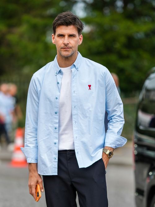 Johannes Huebl trägt ein hellblaues Hemd mit weißem T-Shirt darunter und dunkelblauer Hose auf der Paris Fashion Week.