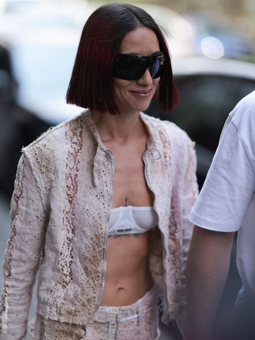 Alexandra Guerain is seen wearing a matching Acne Studios two piece with a beige jacket and beige capri pants, Miu Miu white bra, Acne Studios pink asymmetric bag, white socks and white sneaker before Hed Mayner show during the Menswear Spring/Summer 2024 as part of Paris Fashion Week on June 21, 2023 in Paris, France.