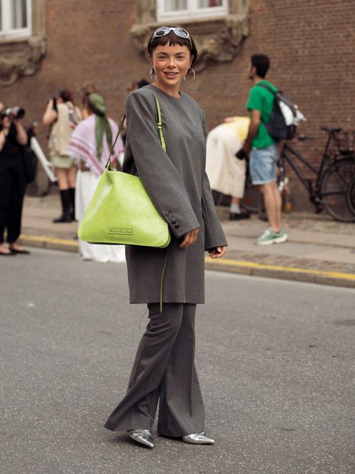 Emma Fridsell wears grey pants, grey long sleeve dress and green bag outside the Gestuz show during day four of the Copenhagen Fashion Week (CPHFW) SS25 on August 08, 2024 in Copenhagen, Denmark.