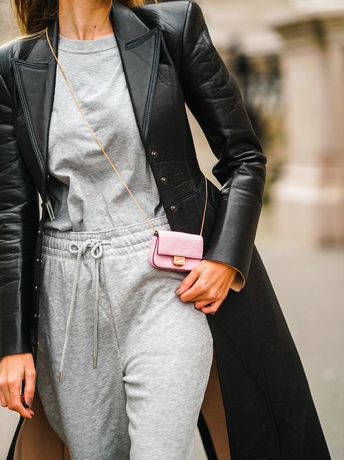 Closeup von einem Streetstyle mit einem schwarzen Ledermantel zu eine rosa Minibag und einem grauen Jogginganzug.