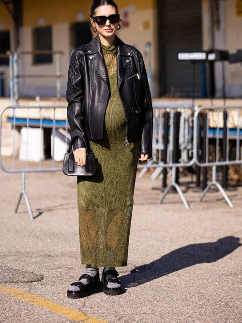 Diletta Bonaiuti trägt ein langes grünes Strickkleid mit Lederjacke, dazu graue Socken mit Sandalen in Mailand.