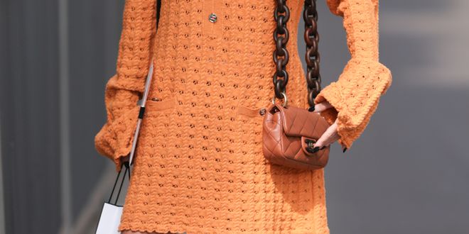 Chloe Harrouche seen outside Chanel show wearing black sunnies, gold hoop earrings, big Chanel chai necklace, orange knitted dress with long sleeves, orange Chanel shoulder bag with big heavy chain and brown sandals during the Haute Couture Fall/Winter 2023/2024 as part of Paris Fashion Week on July 04, 2023 in Paris, France.