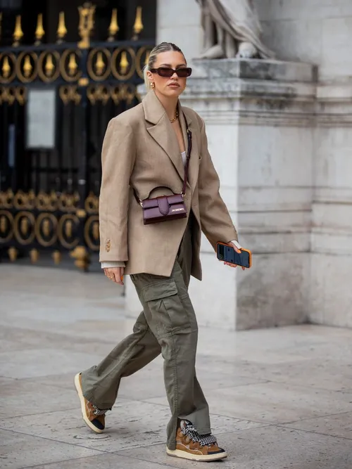Influencerin Caroline Ebo trägt eine Bordeauxrote Jacqumes Tasche zum Beigen Blazer und grüner Cargohose mit Sneakers auf der Paris Fashion Week