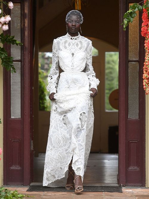 Braut in einem hochgeschlossenen Kleid mit einem Schleier mit Perlen.