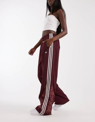 adidas Originals Firebird pantaloni della tuta larghi con ricamo floreale bordeaux-Rosso