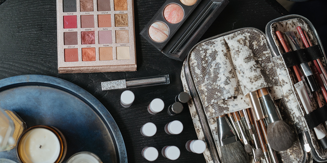 Ein schwarzer Untergrund auf dem viele offene und gebrauchte Make-up-Produkte stehen.