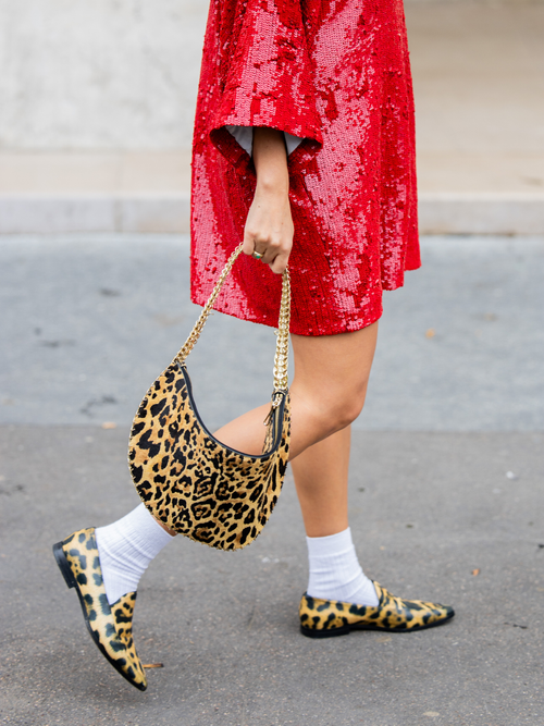Jessica Mercedes Kirschner wears red sequined dress, leopard animal print bag, white socks, flat shoes outside Ganni during Womenswear Spring/Summer 2025 as part of Paris Fashion Week on September 24, 2024 in Paris, France