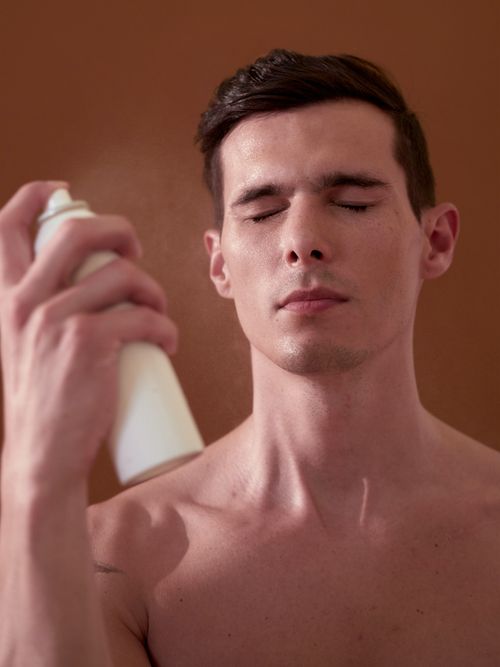 man spraying face with white bottle, Best sunscreens for acne-prone skin