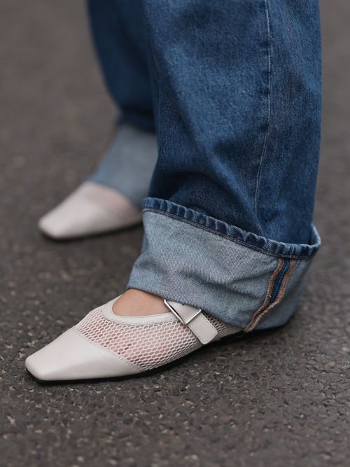 Close-up von einem weißen Mesh Schuhmodell, kombiniert mit einer Jeanshose.