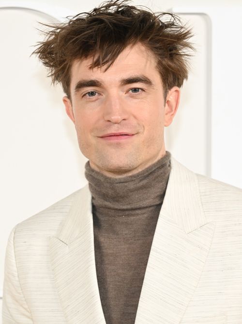 Robert Pattinson trägt einen weißen Anzug mit grauen Rollkragen auf einer Filmpremiere in Los Angeles.