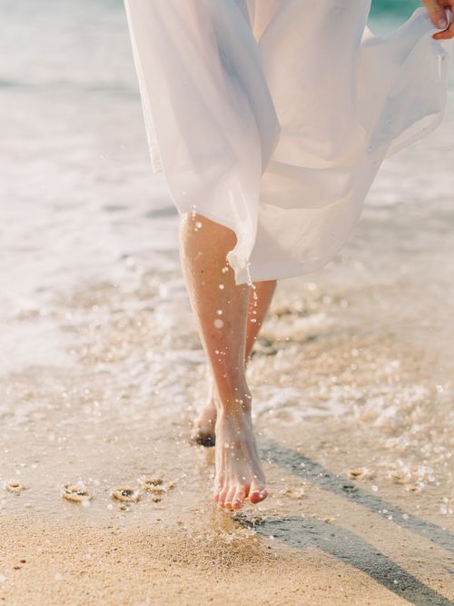 Frau geht am Strand und im Meer entlang spazieren