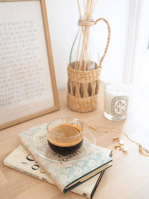 Closeup einer Komode mit zwei Büchern, einer Tasse Kaffee und einem gerahmten Bild.