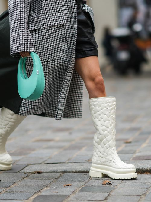 Close-up von weißen Valentino-Boots zu einem karrierten Blazer und einer türkisen Tasche.