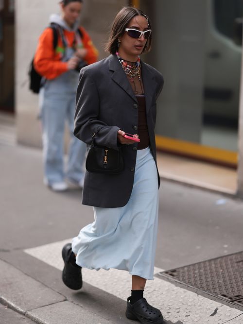 A fashion week guest seen wearing a blue skirt with a blazer and crocs, outside The Row during Paris Fashion Week on September 28, 2022 in Paris, France.
